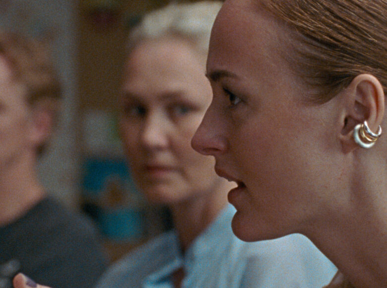 Zbliżenie na twarze trzech rozmawiających ze sobą osób w jasnym pomieszczeniu.