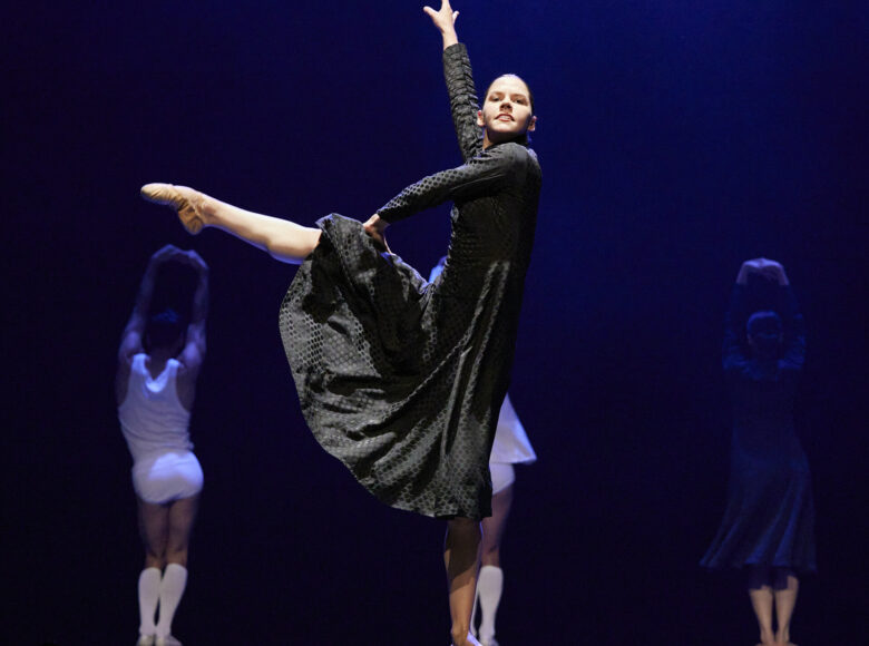 Grupa tancerzy na scenie. Na pierwszym planie tancerka w tanecznej pozie.
