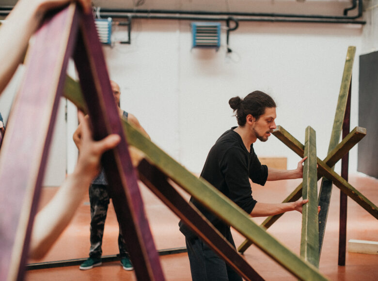 Jasne pomieszczenie. Mężczyzna ustawia konstrukcję z listewek.