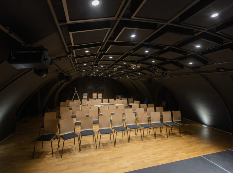 Na zdjęciu niewielka sala teatralna z krzesłami na widowni. W sali nikogo nie ma.