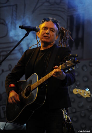 Na scenie muzyk grający na gitarze.