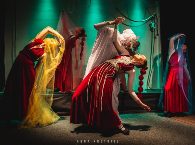 Przedstawienie teatralne. Grupa tańczących kobiet w antycznych strojach.