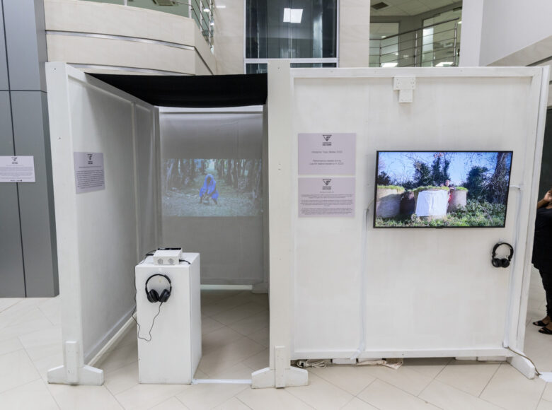 Wnętrze nowoczesnego budynku użyteczności publicznej. Na wiszących na ścianie ekranach wyświetlane są filmy.