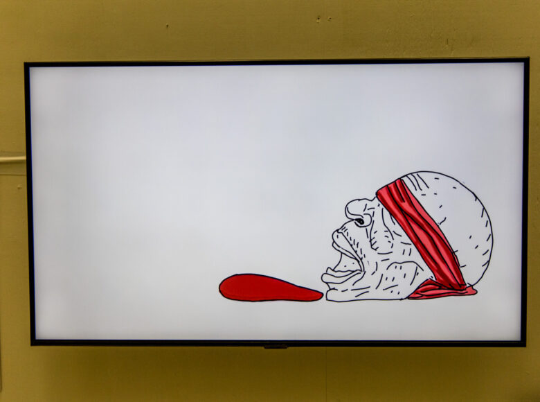 Zbliżenie na rysunek wiszący na ścianie. Rysunek przedstawia twarz z zawiązanymi oczami.