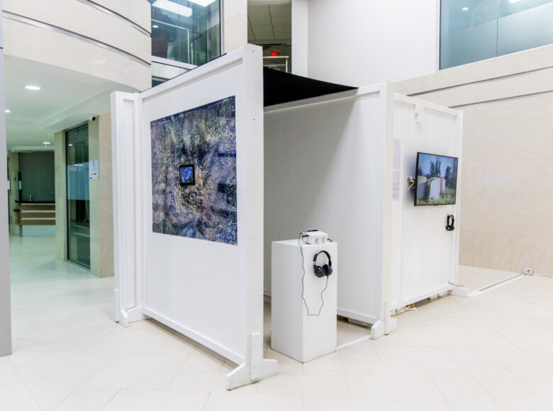 Wnętrze galerii sztuki współczesnej. Na ścianach wiszą ekrany, na których wyświetlane są filmy.