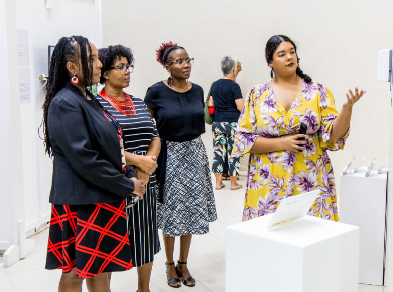 Wnętrze galerii sztuki współczesnej. Grupa kobiet ogląda jakiś obiekt sztuki, wiszący na ścianie.