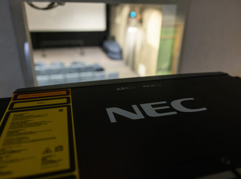 Zbliżenie na projektor filmowy. Pokazana jest naklejka z oznaczeniami fabrycznymi naklejona na projektor.