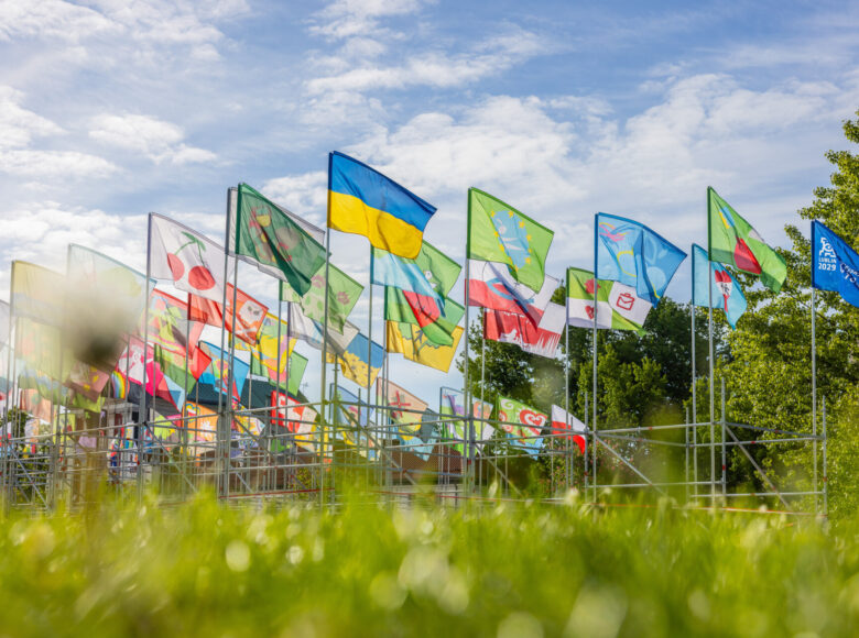 Plac Litewski w Lublinie. Na placu stoi rusztowanie. Do rusztowania przyczepionych jest kilka rzędów kolorowych chorągwi. Na jednej z chorągwi napis: "Lublin dwa tysiące dwadzieścia dziewięć. Europejska Stolica Kultury." Widać także flagę Polski.