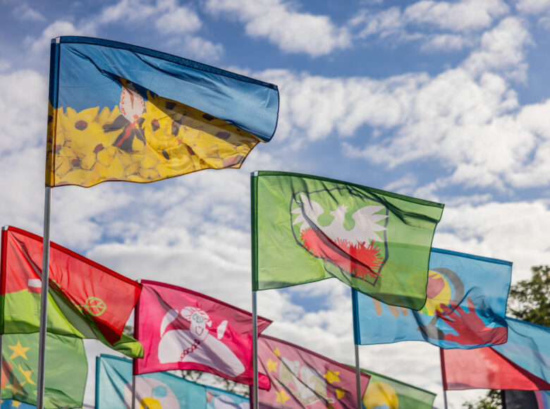 Na tle nieba powiewa kilkanaście kolorowych chorągwi.