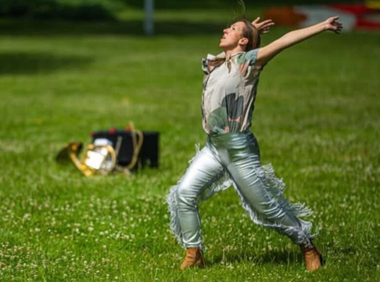 Tancerka tańca współczesnego tańczy na trawie w plenerze.