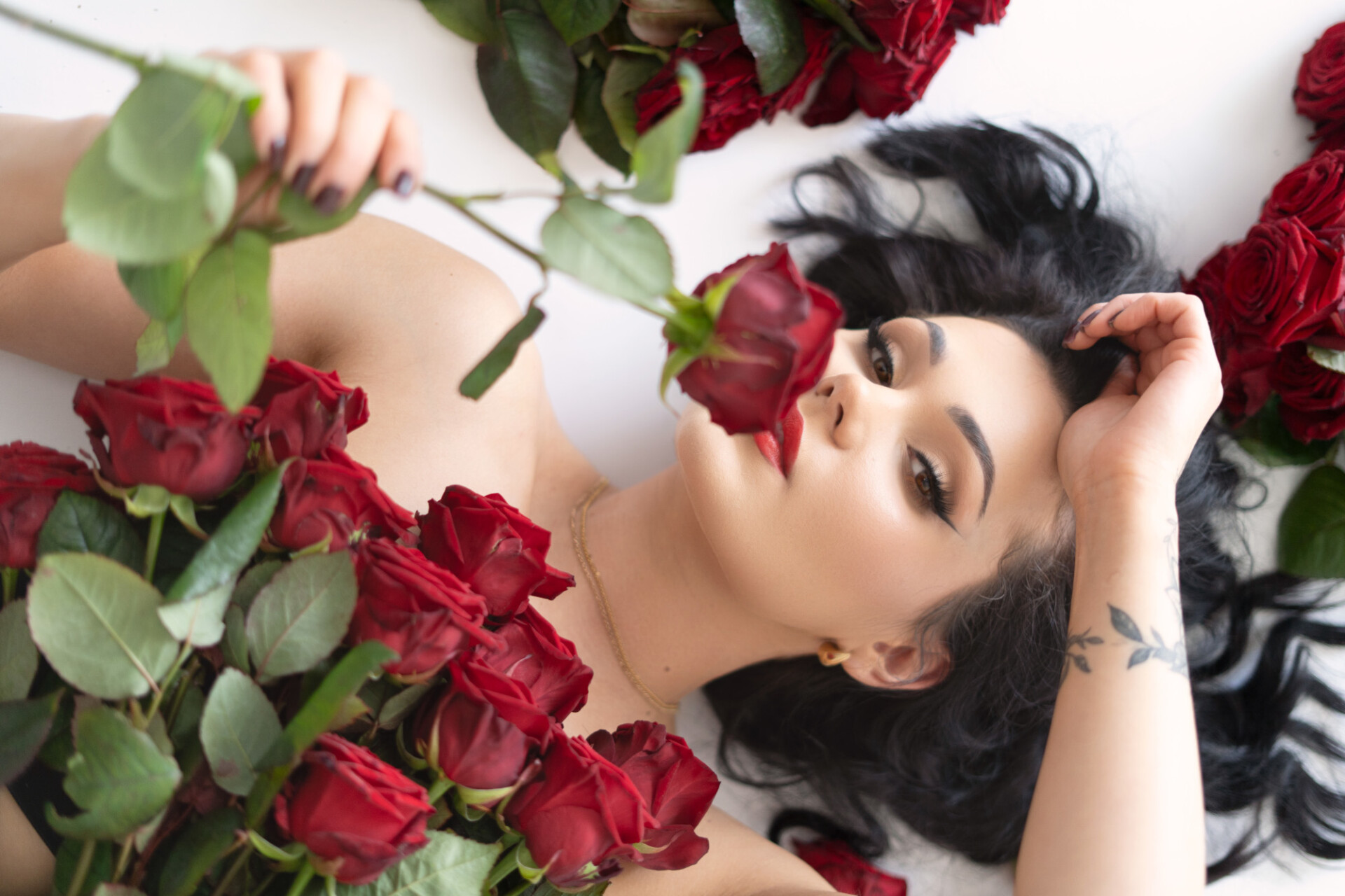 Na kolorowej fotografii widzimy popiersie, leżącej na&nbsp;białej płaszczyźnie, młodej nagiej, patrzącej w&nbsp;obiektyw modelki, o&nbsp;regularnych rysach, z&nbsp;czarnymi włosami i&nbsp;starannym makijażem. Piersi kobiety przykrywają ciemnoczerwone róże. Modelka trzyma też czerwoną różę w&nbsp;prawej dłoni i&nbsp;wącha ją. Lewą rękę, na&nbsp;której jest widoczny tatuaż, opiera dłonią o&nbsp;czoło. Na&nbsp;szyi ma delikatny złoty łańcuszek. Obok&nbsp;widać fragmenty bukietów ciemnoczerwonych róż.