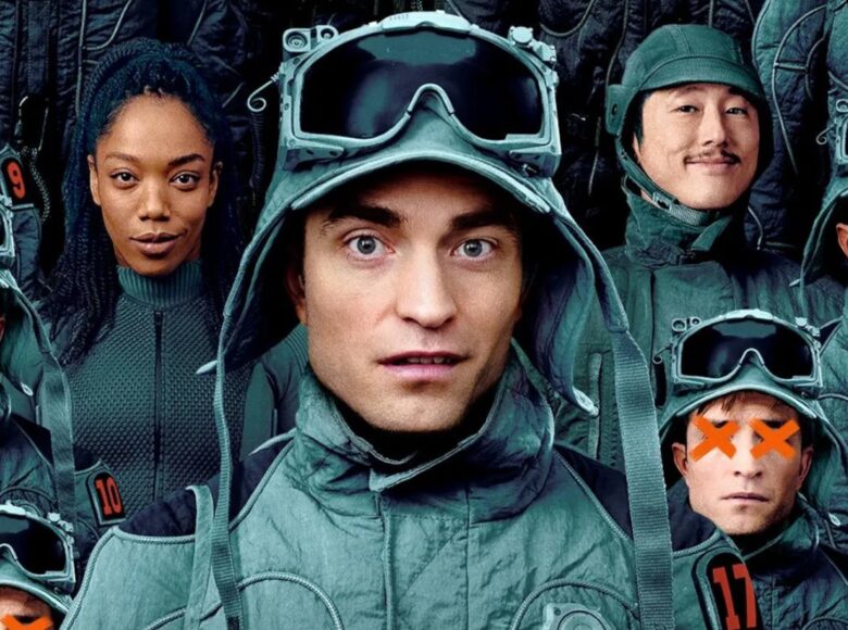 Zbliżenie na grupę ludzi, kilku mężczyzn i kobietę. Ubrani są w szare kurtki i nakrycia głowy. Wszyscy patrzą prosto w obiektyw. Kilku spośród mężczyzn ma zakryte oczy.