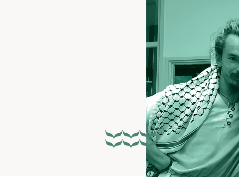 Młody mężczyzna pozujący do fotografii. Za nim fragment pomieszczenia.