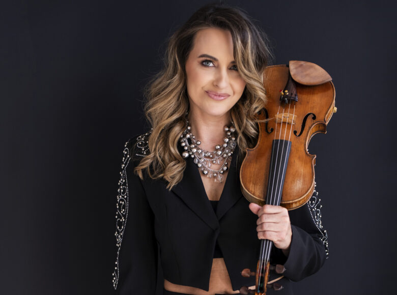 Fotograficzny portret kobiety w średnim wieku, trzymającej w ręku skrzypce.