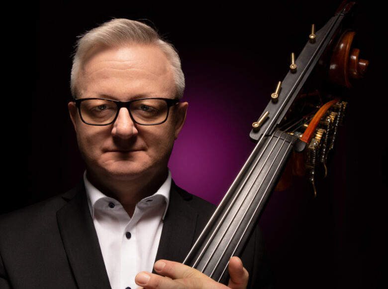 Fotograficzny portret mężczyzny w średnim wieku, trzymającego kontrabas.