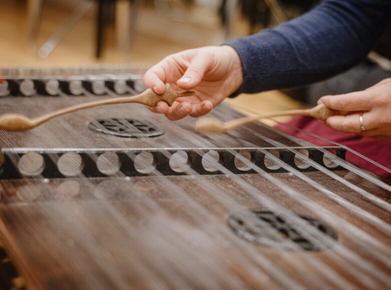 Zbliżenie na ręce osoby, grającej na cymbałach.