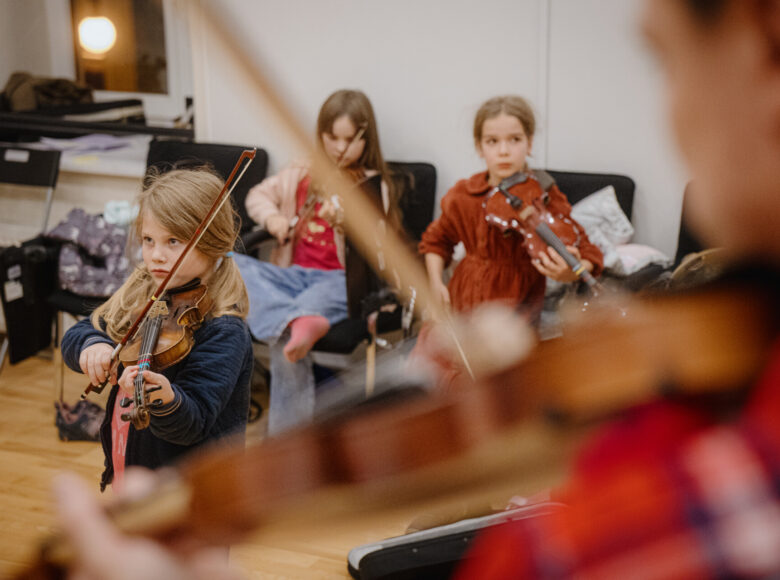 W pomieszczeniu kilka dziewczynek grających na skrzypcach.