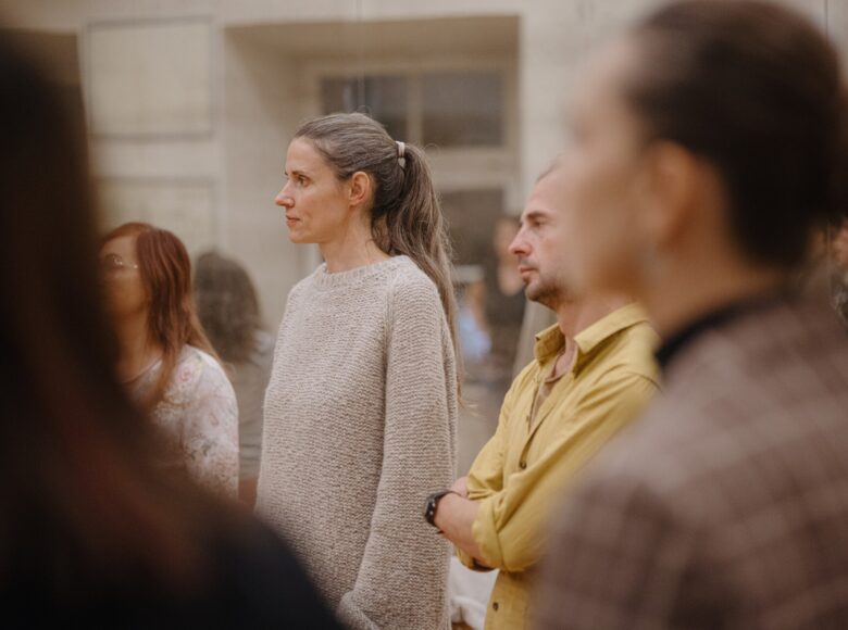 Zbliżenie na kilka osób, stojących obok siebie w pomieszczeniu.