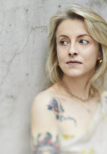 Fotograficzny portret młodej kobiety na tle szarej ściany.