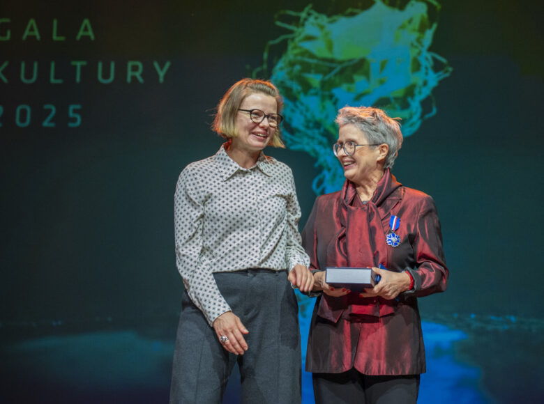 Uroczystość na scenie. Na pierwszym planie stoją obok siebie dwie elegancko ubrane kobiety. Jedna z nich to Anna Nawrot, założycielka Galerii Białej w Lublinie. Z tyłu sceny umieszczony jest napis "Gala Kultury dwa tysiące dwadzieścia pięć".