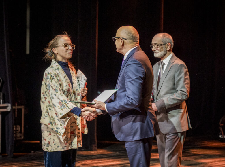 Uroczystość na scenie. Prezydent Lublina Krzysztof Żuk wręcza dyplom kobiecie ubranej w kimono. Obok stoi lubelski radny Jarosław Pakuła.