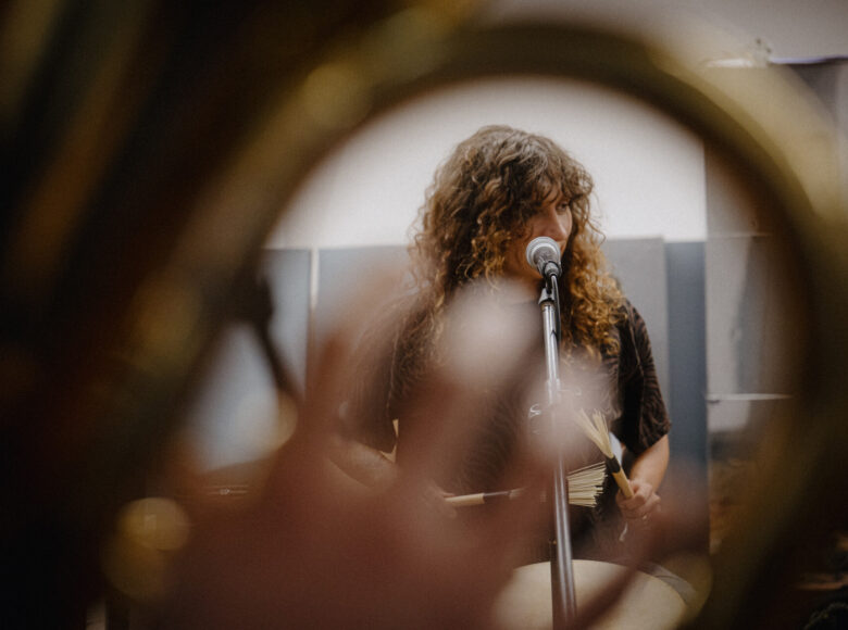 W pomieszczeniu kobieta grająca na bębnach.