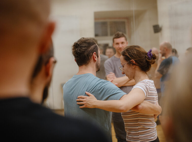 W sali tańcząca para, dookoła stoi kilka osób.