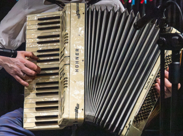 Zbliżenie na ręce mężczyzny grającego na akordeonie.