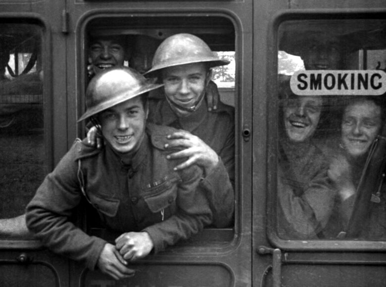 Kadr z filmu czarno biały. Zbliżenie na okna pociągu, z których wychylają się żołnierze patrząc do kamery.