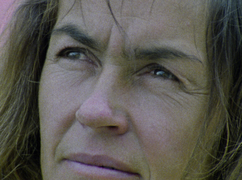 Kadr z filmu. Zbliżenie na twarz kobiety patrzącej do góry na coś, co znajduje się poza kadrem.