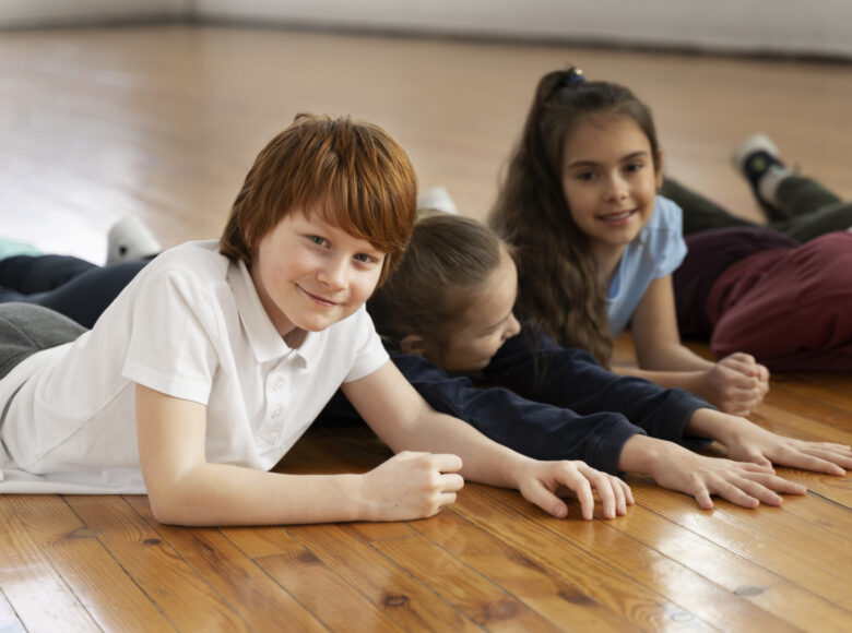 Kilkoro kilkuletnich dzieci, leżących obok siebie na brzuchach na podłodze.