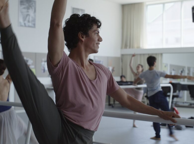 Grupa tancerek i tancerzy tańca klasycznego, ćwiczących w sali do ćwiczeń tanecznych.