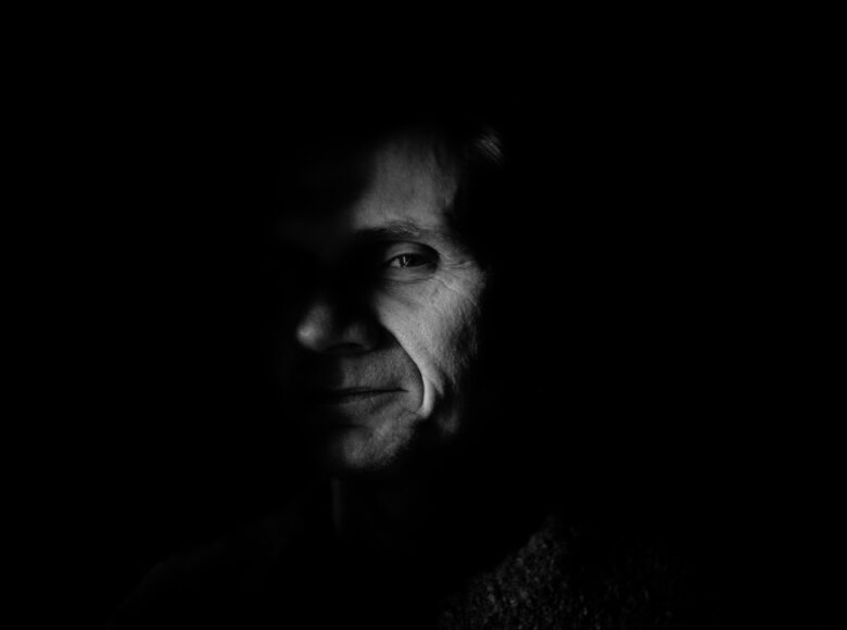 Czarno biały portret fotograficzny. Przedstawia twarz starszego mężczyzny.