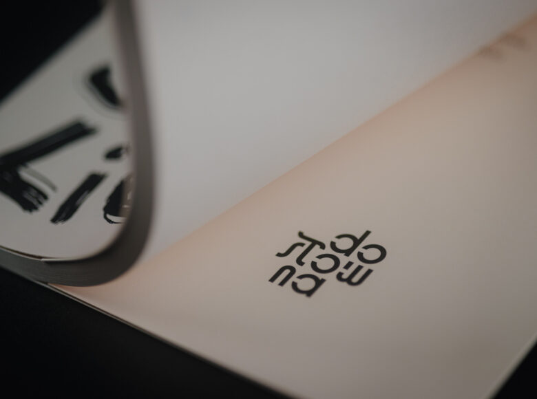 Zbliżenie na książkę otwartą na stronie z wydrukowanym logotypem Księgarni Dosłownej.