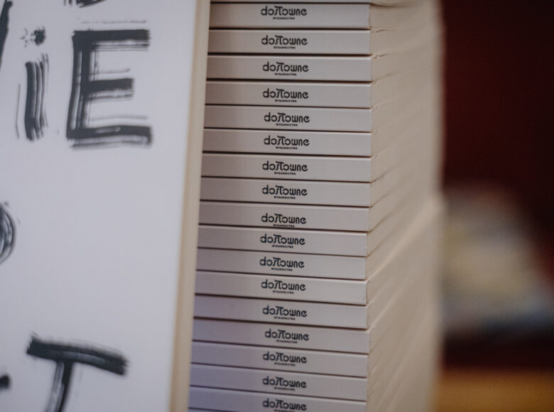 Zbliżenie na kilka egzemplarzy nowej książki Wydawnictwa Dosłownego. Jeden z egzemplarzy stoi oparty o pozostałe, ułożone jeden na drugim.