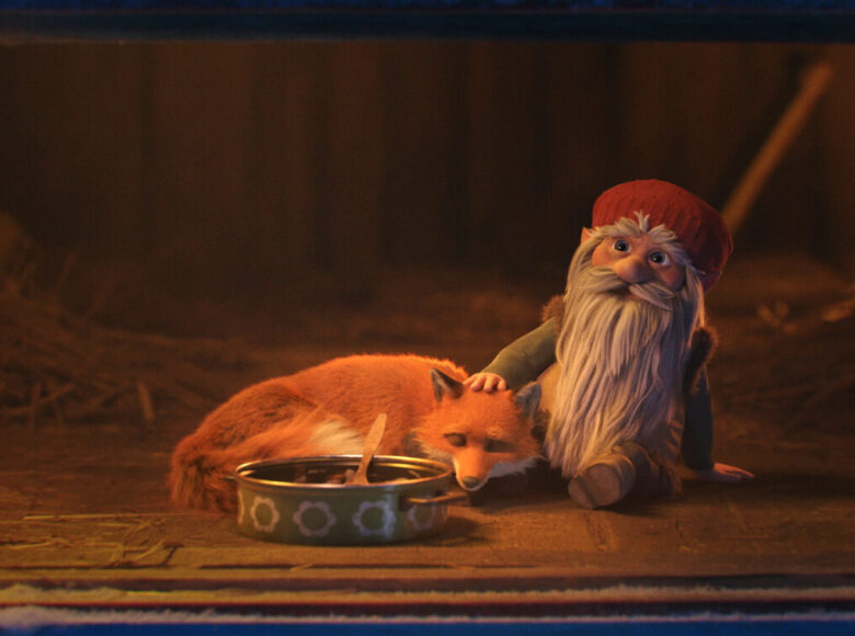 Kadr z filmu animowanego. Wnętrze stodoły. Na pierwszym planie leży lisek, a obok siedzi skrzat, głaszczący liska po głowie. Przed liskiem stoi naczynie z jedzeniem.