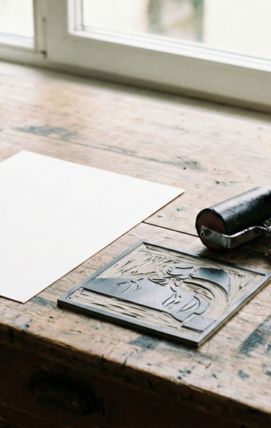 Zbliżenie na blat stołu warsztatowego, na którym leżą przyrządy do linorytu.