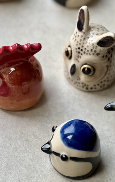 Na blacie stoi kilka kolorowych, ceramicznych figurek. Przedstawiają one ptaszki.
