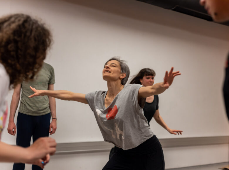 Kilka osób gimnastykujących się w sali do ćwiczeń gimnastycznych.