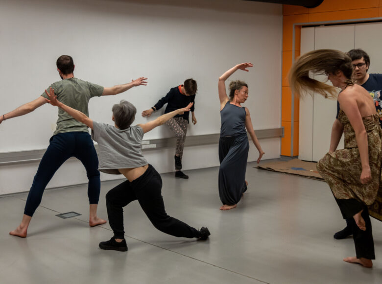 Kilka osób gimnastykujących się w sali do ćwiczeń gimnastycznych.