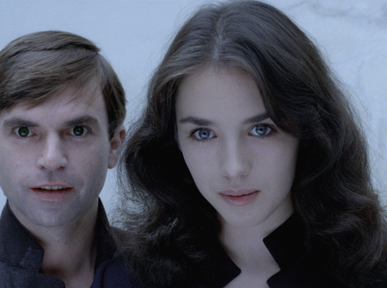 Zbliżenie na twarze młodej kobiety i młodego mężczyzny stojących obok siebie i patrzących na widza.