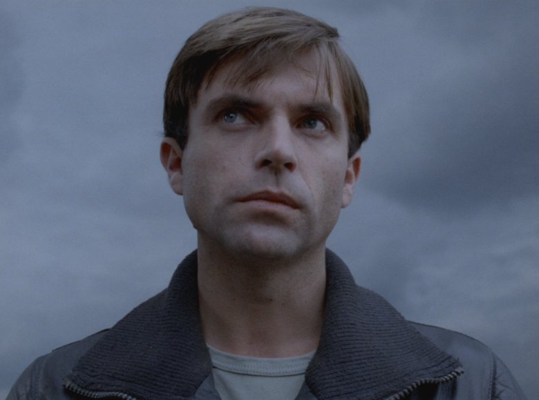 Zbliżenie na twarz młodego mężczyzny patrzącego na coś w górę z zastanowieniem.