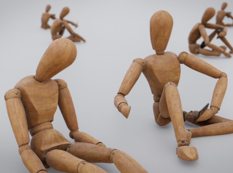 Kilka drewnianych manekinów siedzących na białej podłodze i na białym tle.