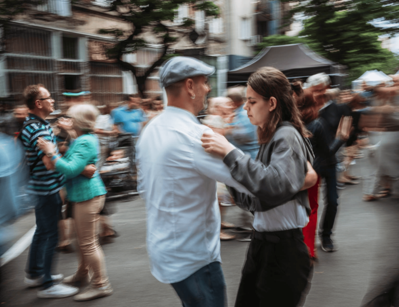 Letni dzień. Na miejskiej ulicy ludzie tańczą w parach.