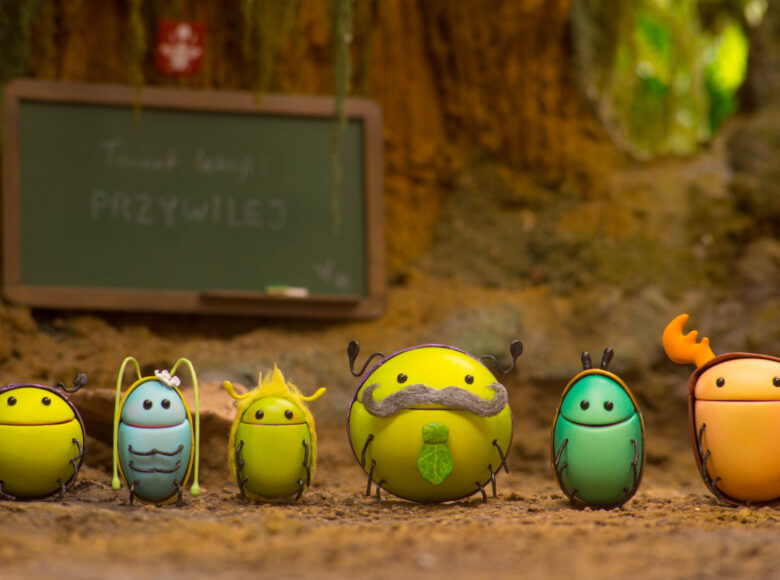 Kadr z filmu animowanego. W lesie sześć żuczków stojących w rzędzie przodem do nas.