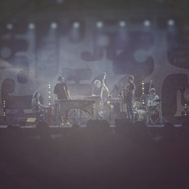 Na scenie grupa muzyków dżezowych grających koncert.