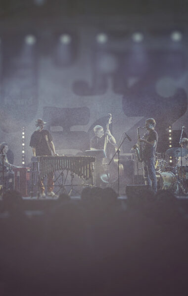 Na scenie grupa muzyków dżezowych grających koncert.