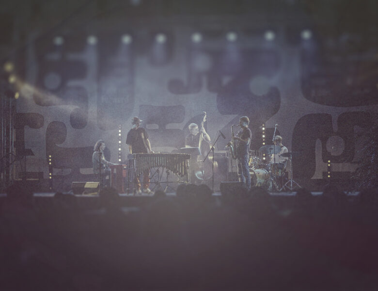 Na scenie grupa muzyków dżezowych grających koncert.