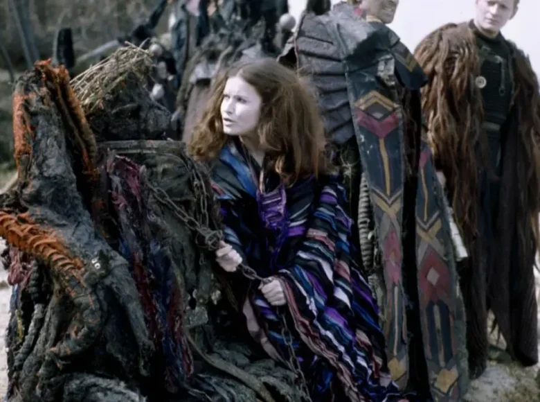 W lesie, na brzegu rzeki stoją obok siebie dwie kobiety i mężczyzna w kolorowych, szamańskich strojach.