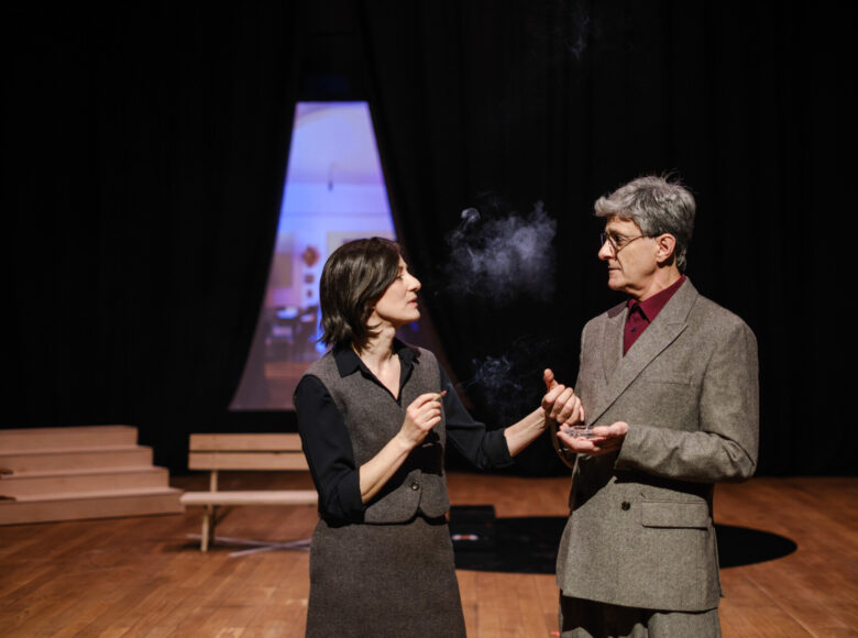 Przedstawienie teatralne. Na scenie stoją kobieta i mężczyzna, rozmawiając ze sobą.